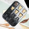 A baking pan with bear-shaped molds, some filled with batter and one with chocolate chips, alongside piping bags and wooden spoons. Voir les images du produit
