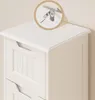 Close-up of the top of a white wooden cabinet with drawers, showing a detail of the anti-tip hardware. Produktbild-Vorschau