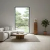 A living room scene with a sectional sofa, coffee table, rug, and a decorative wooden column with a sculpture and a plant. Voir les images du produit