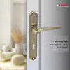 A close-up of a bronze-colored door handle on a white door, with a blurred background of a room interior. Produktbild-Vorschau