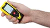 A hand holding a yellow and black laser distance meter. Produktbild-Vorschau