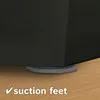 A close-up of the bottom corner of a dark gray appliance, showing gray suction feet on a wooden surface. Produktbild-Vorschau
