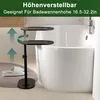 A black adjustable height side table next to a white bathtub, with slippers on a rug in the foreground. Produktbild-Vorschau