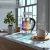 A glass electric kettle with colorful LED lighting is shown on a kitchen counter next to a mug. Produktbild-Vorschau
