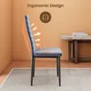 A side view of a gray velvet dining chair with orange graphic overlays indicating ergonomic support, placed on a patterned rug in a room with an orange wall and a wooden table in the background. Náhľad obrázku produktu