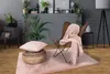 A cozy living room scene with a butterfly chair, a pouf, a pillow, and a blanket. Produktbild-Vorschau