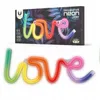 A neon LED sign shaped like the word "love" with a rainbow color gradient, shown both on its packaging and as a standalone product. Anteprima dell’immagine prodotto