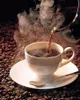 A cup of coffee is being poured into a white cup, surrounded by coffee beans. Produktbild-Vorschau