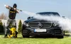 A person is pressure washing a black Mercedes-Benz car on a grassy lawn. Produktbild-Vorschau