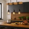 A modern kitchen scene featuring a wooden island with a pendant light fixture above, a pot on a stovetop, and a cutting board with vegetables. Náhľad obrázku produktu