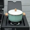 A green pot with a white lid sits on a black gas burner. Produktbild-Vorschau