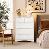 A bedroom scene with a white dresser, chair, plant, and bed. Podgląd zdjęcia produktu