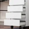 Close-up view of a white set of drawers with black wheels. Voir les images du produit