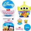 A collage of Disney Snackles surprise toys, including a large ball, a plush alien, and smaller collectible figures and packaging. Produktbild-Vorschau