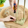 A person is screwing a hairpin leg onto a wooden surface. Produktbild-Vorschau