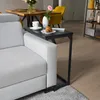A C-shaped side table is placed next to a sofa, holding a cup of coffee and a croissant. Produktbild-Vorschau