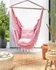 A pink hammock chair with cushions hangs on a patio, with plants and decor around it. Podgląd zdjęcia produktu