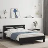 A black wooden bed frame with a headboard, made of wood composite, is shown in a bedroom setting. The bed is made up with white bedding and a blue throw blanket. There are two framed pictures on the wall above the bed, and a small bedside table to the left Anteprima dell’immagine prodotto
