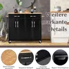 A black kitchen cart with a wooden top is shown, with close-up insets highlighting its features. The background includes a wall and a white cabinet. Náhľad obrázku produktu