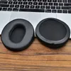 Two black ear pads are placed on a wooden surface in front of a laptop keyboard. Voir les images du produit