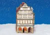A miniature building, likely a Christmas decoration, sits in artificial snow against a starry blue background. Produktbild-Vorschau
