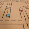 A toy road mat with three toy cars on it. Produktbild-Vorschau