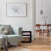 A mini fridge filled with cans and bottles is placed next to a couch in a living room. Voir les images du produit