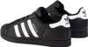 A pair of black Adidas Superstar sneakers with white stripes and gold accents. Voir les images du produit