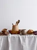 A collection of wooden and ceramic tableware items arranged on a white tablecloth. Produktbild-Vorschau