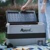 A person is opening the lid of a portable cooler box placed on a picnic blanket outdoors. Produktbild-Vorschau