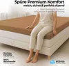 A person sitting on a bed with a fitted sheet. Produktbild-Vorschau