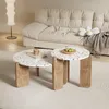 A modern living room scene with two terrazzo coffee tables in the foreground, a tufted sofa in the background, and a floor lamp. Voir les images du produit
