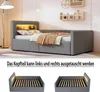 A grey upholstered bed with a built-in headboard shelf illuminated by yellow LED lights. The bed is made up with pillows and a brown and beige throw blanket. Below the main image, two smaller images show the bed frame with the mattress removed, demonstrati Produktbild-Vorschau