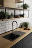 A modern kitchen sink area with a faucet, wooden countertop, and shelves with plants and kitchenware. Produktbild-Vorschau