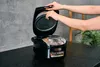 Hands adjusting a component inside an open rice cooker. Produktbild-Vorschau