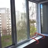 A red safety ladder is placed on a windowsill with a view of apartment buildings and trees outside. Voir les images du produit