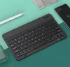 A black portable Bluetooth keyboard is laid out on a two-toned green surface, with a white stylus pen and a black smartphone visible. Náhled obrázku produktu