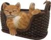 A decorative figurine of a sleeping orange cat in a woven basket. Produktbild-Vorschau