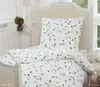 A close-up view of a bed with white bedding featuring a red floral pattern. Produktbild-Vorschau