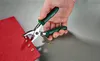 A hand is using a tool to punch holes in a red fabric. Produktbild-Vorschau