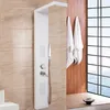 A modern white shower panel with integrated showerhead, hand shower, and controls, set against a tiled wall and a window with a view of the sea. Náhled obrázku produktu