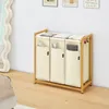A laundry basket with three compartments is shown in a room with a wooden floor and a white wall. Anteprima dell’immagine prodotto