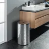 A modern bathroom with a stainless steel laundry hamper next to a wooden vanity with a white sink. Produktbild-Vorschau