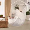 A white hammock chair with ruffled edges hangs in a bright, modern living room with curtains, a plant, and a small table with a fruit basket. Náhled obrázku produktu