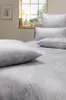 A bed with pillows and bedding, near a window with a lamp and a framed picture on the wall. Produktbild-Vorschau