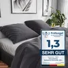 A bed with dark gray bedding and pillows, with a promotional badge on the right. Produktbild-Vorschau
