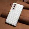 A white quilted phone case with a pink camera housing is placed on a brown leather background. Produktbild-Vorschau