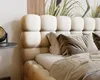 A close-up view of a bed with a tufted headboard and pillows. Náhled obrázku produktu