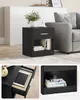 A black side table with a drawer and shelf next to a gray sofa. Náhled obrázku produktu