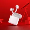 A pair of white wireless earbuds and their charging case are displayed against a vibrant red background, with a red telescope and stacked red boxes in the background. Náhľad obrázku produktu